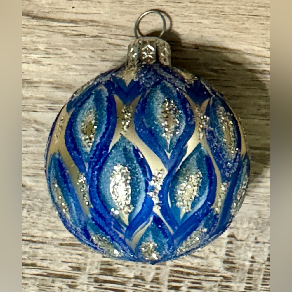 A hand-painted glass Christmas tree ornament in a blue and silver color scheme.